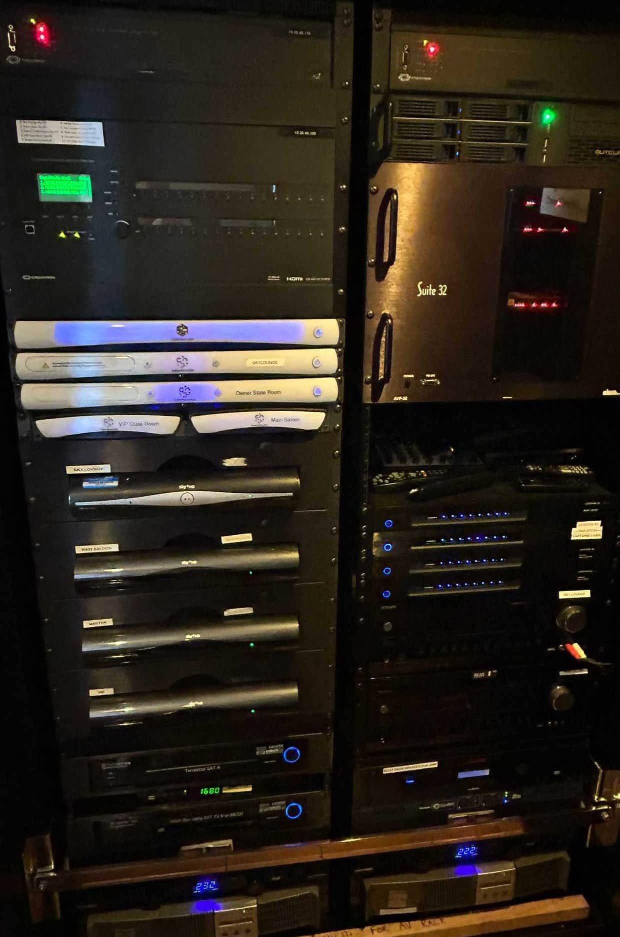 A card-based Crestron DigitalMedia matrix switcher in a superyacht AV rack, with per-zone media players and satellite receivers stacked below it