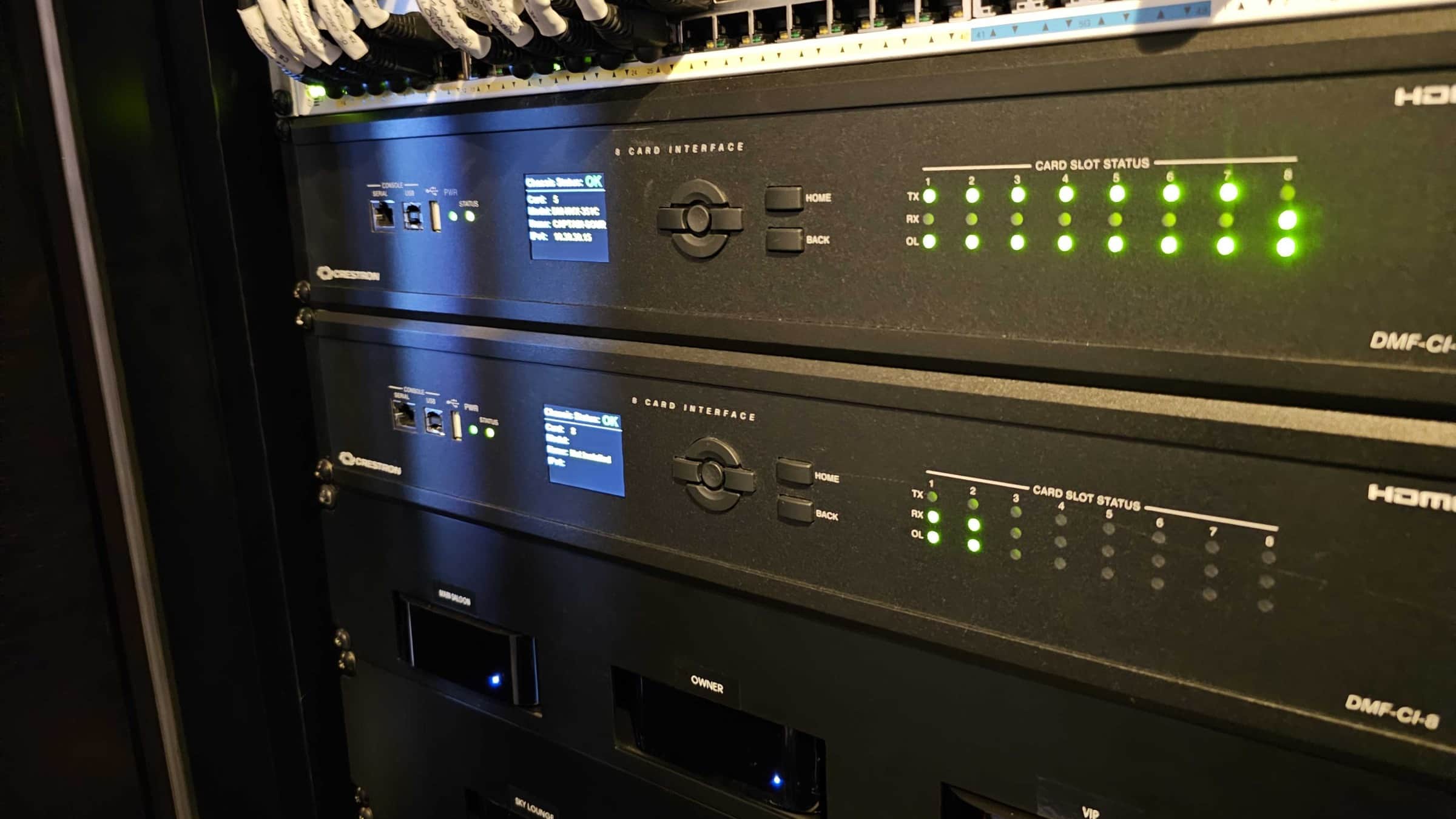 Two Crestron DMF-CI-8 card chassis populated with DM NVX cards, mounted below a 48-port managed switch in a superyacht AV rack